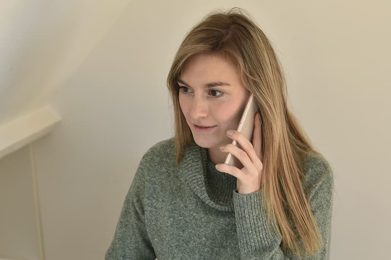 Femeie care vorbește la telefon de la biroul ei, în fața calculatorului
